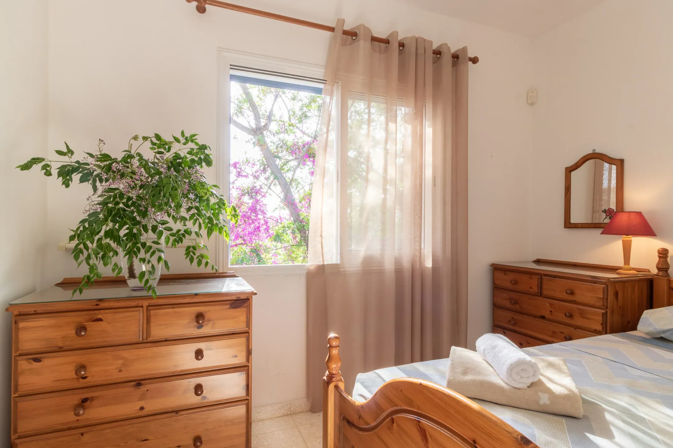 Eine Kiefernkommode und die Bougainvillea vor dem Fenster